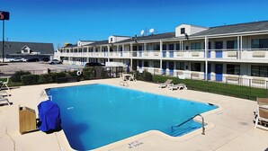 A hotel with a swimming pool, outdoor seating, and a fenced area. - Studio 6 Webster, TX Houston - NASA Lake (Webster)