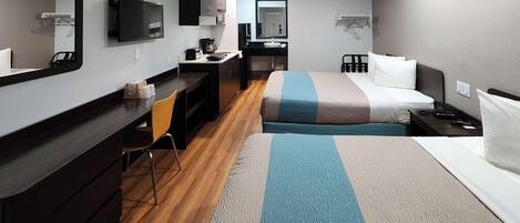 A hotel room with a desk, chair, bed, and a television.
