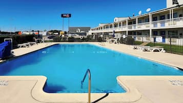 Een buitenzwembad, parasols bij het zwembad en ligstoelen