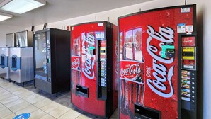 A row of Coca-Cola vending machines in a commercial setting. - Studio 6 Webster, TX Houston - NASA Lake (Webster)