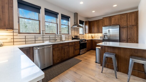 A modern kitchen with wooden cabinets, stainless steel appliances, and large windows. - Open-Concept Townhome Next to Blue River w/ Private Wrap-Around Patio! (Silverthorne)