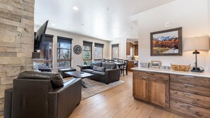 A spacious living area with a fireplace, a sofa, a coffee table, and a dining area with a table and chairs. - Open-Concept Townhome Next to Blue River w/ Private Wrap-Around Patio! (Silverthorne)