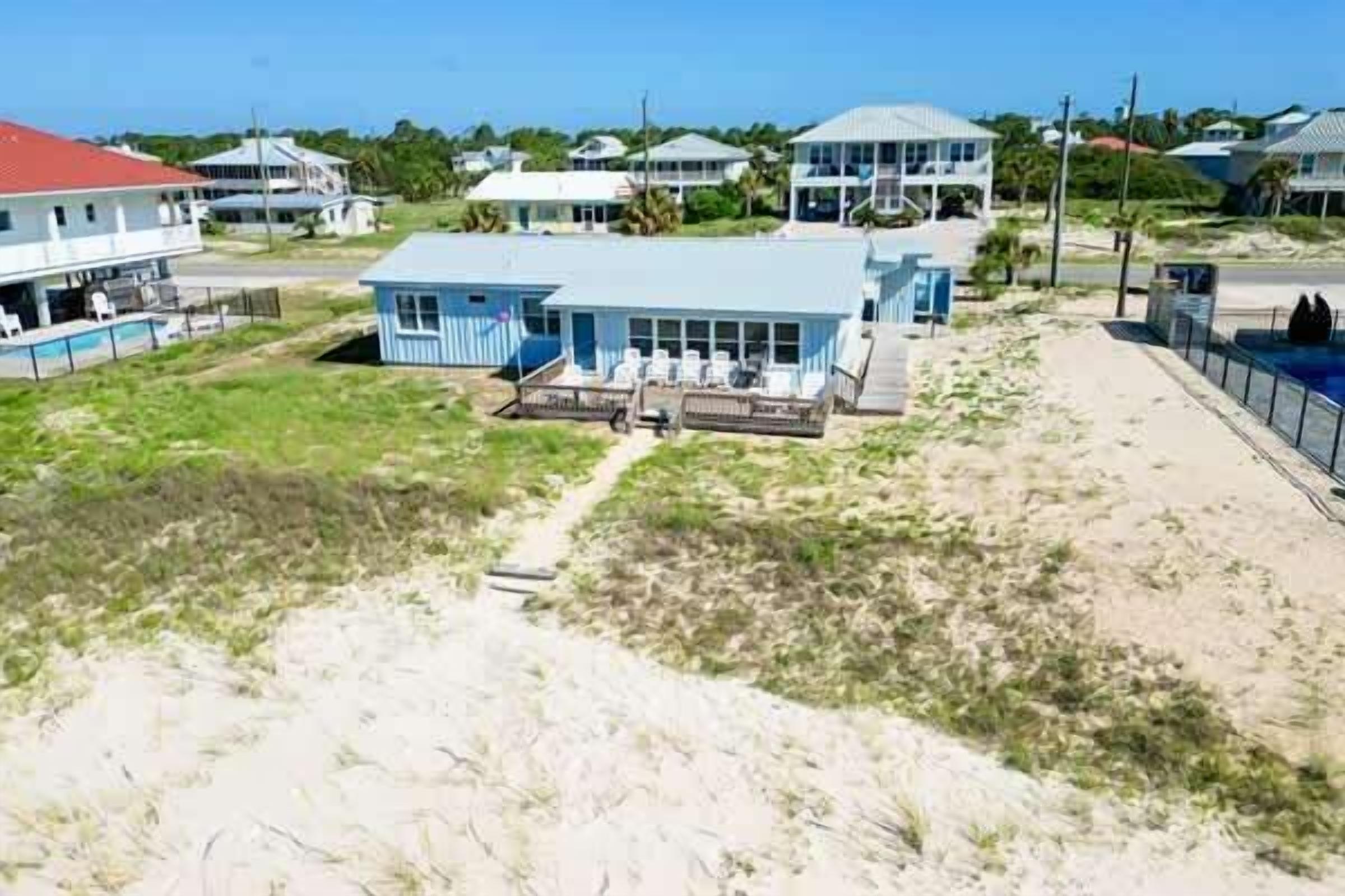 A coastal property with a large house, a swimming pool, and a beach area.