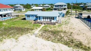 A coastal property with a large house, a swimming pool, and a beach area.