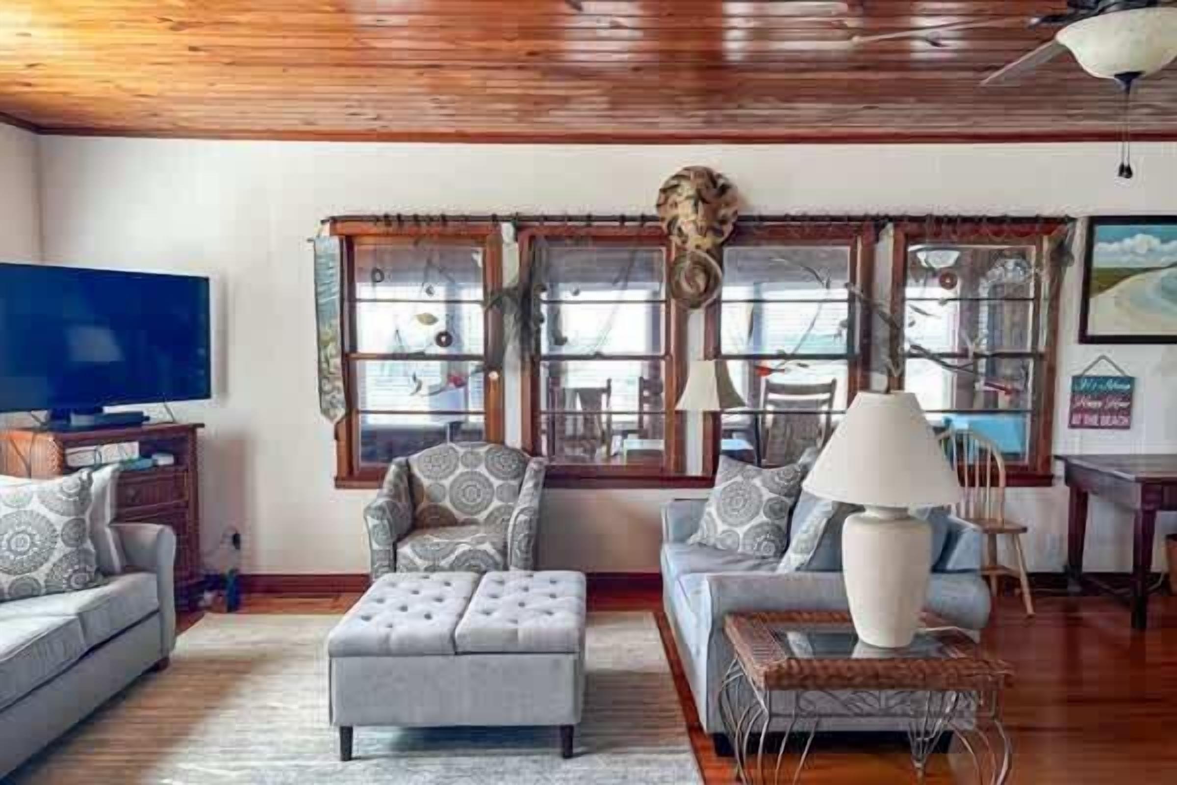 A living room with a television, patterned sofas, a coffee table, and a decorative headpiece on the wall.
