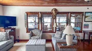 A living room with a television, patterned sofas, a coffee table, and a decorative headpiece on the wall.