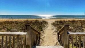 Un sentier qui mène à une plage, avec un ciel dégagé.