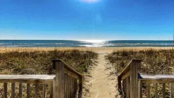 A pathway leading to a beach with a clear sky.