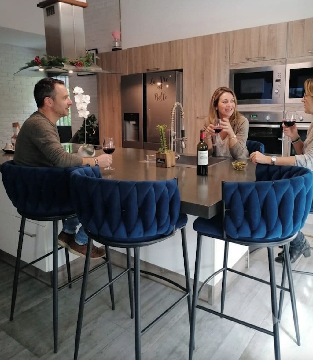 A modern kitchen with a central island, bar stools, and stainless steel appliances.