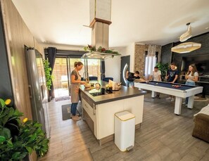 Une cuisine moderne dotée d’un îlot central, d’une table de billard et d’un coin repas.