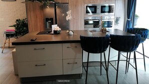 Une cuisine moderne dotée d’un îlot central, de deux fours, d’un four à micro-ondes et d’un coin repas avec quatre chaises.