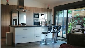 Une cuisine moderne avec des meubles blancs, un îlot central et des tabourets de bar.