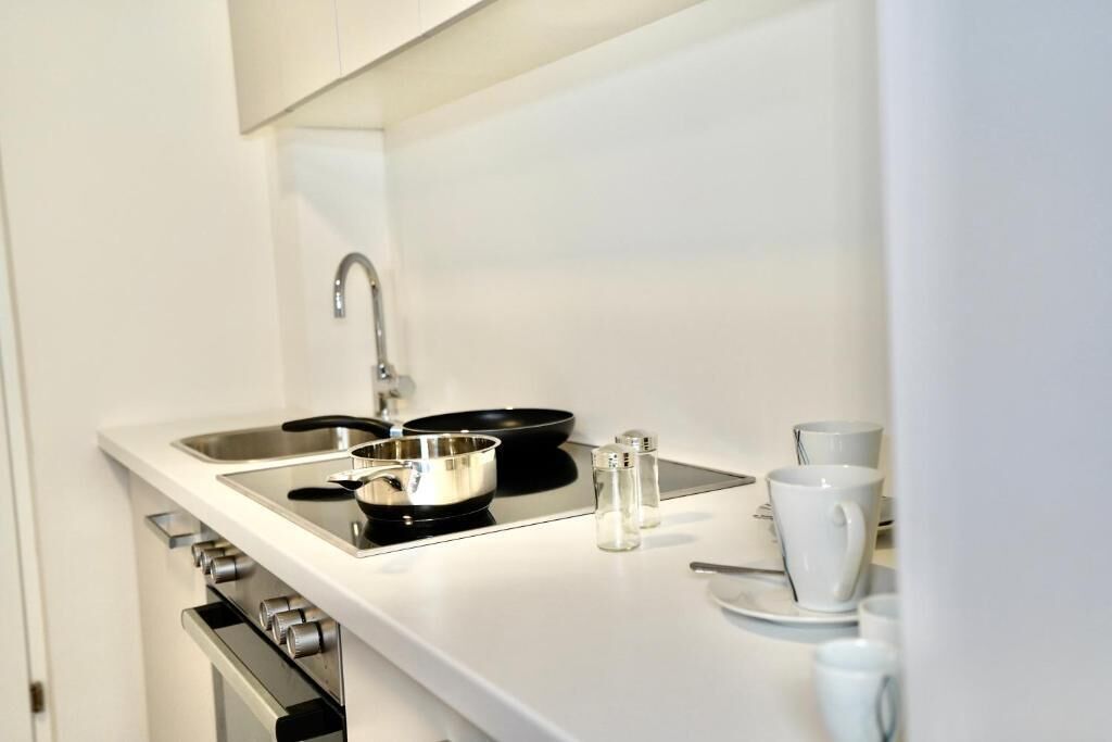 A modern kitchen with a stainless steel sink, a black frying pan, and salt and pepper shakers.