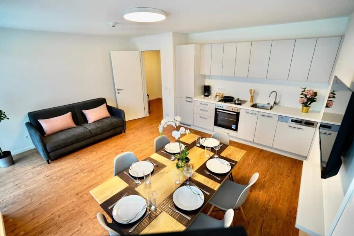 En moderne lejlighed med spiseplads, sofa og køkken.