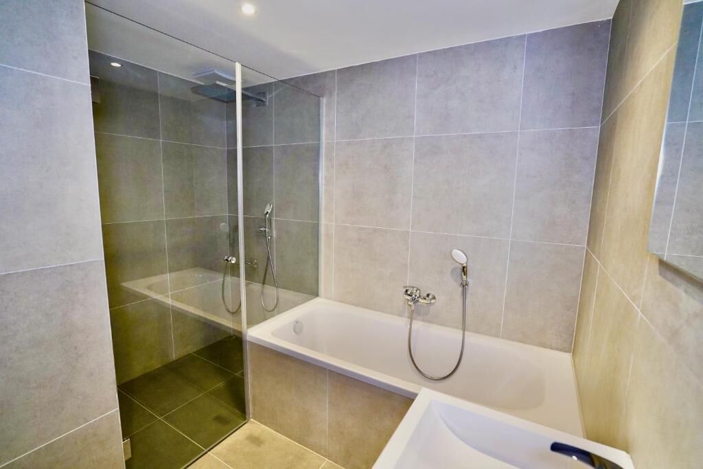 A modern bathroom with a glass-enclosed shower, a standalone bathtub, and a separate sink area.