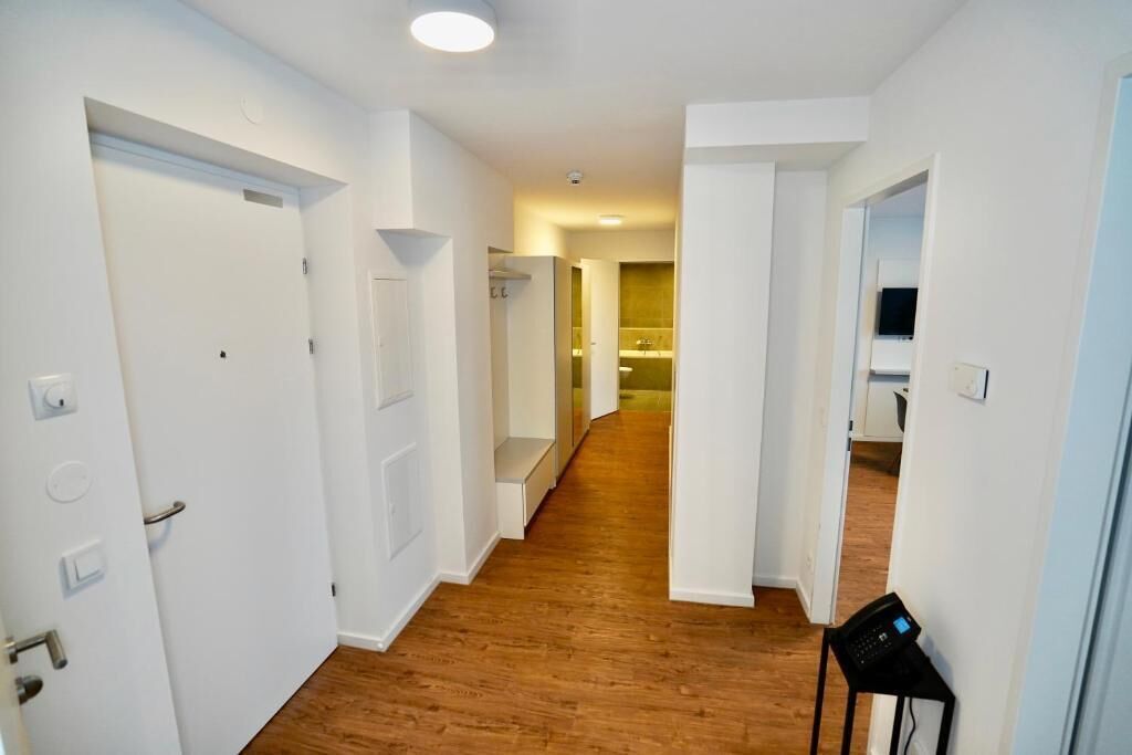 Un couloir doté d’un plancher en bois, de murs blancs et de portes donnant accès à différentes pièces.