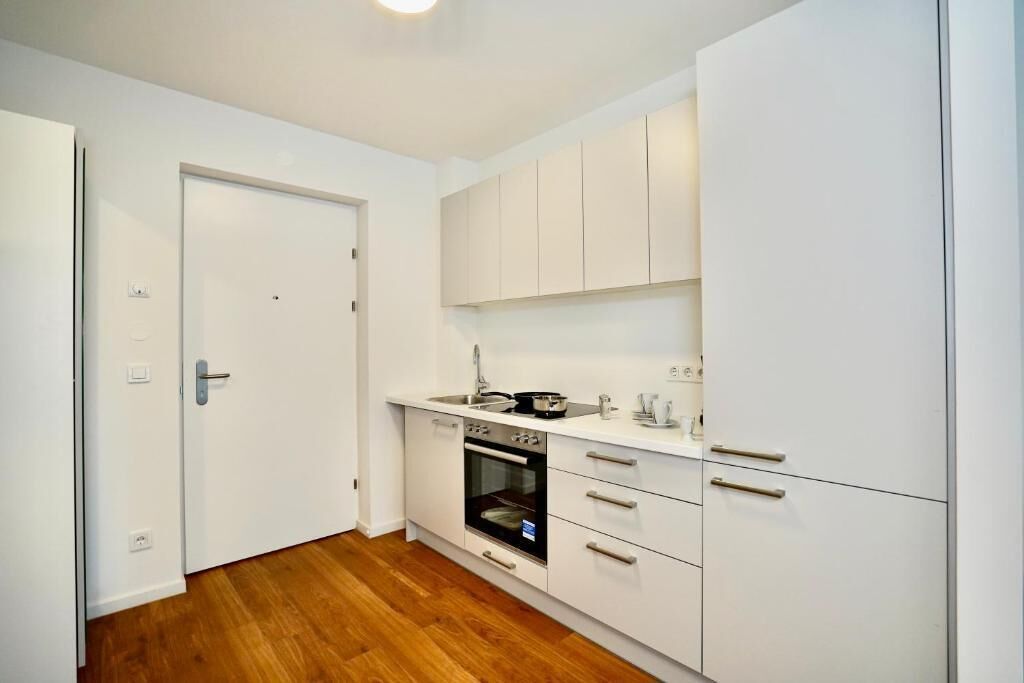 A compact kitchen with white cabinets, a built-in oven, and a sink.