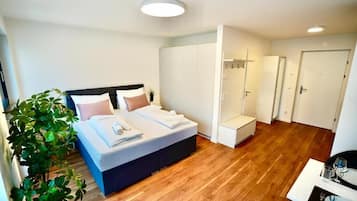 Een moderne slaapkamer met een bed, een kledingkast, een zithoek en een plant.
