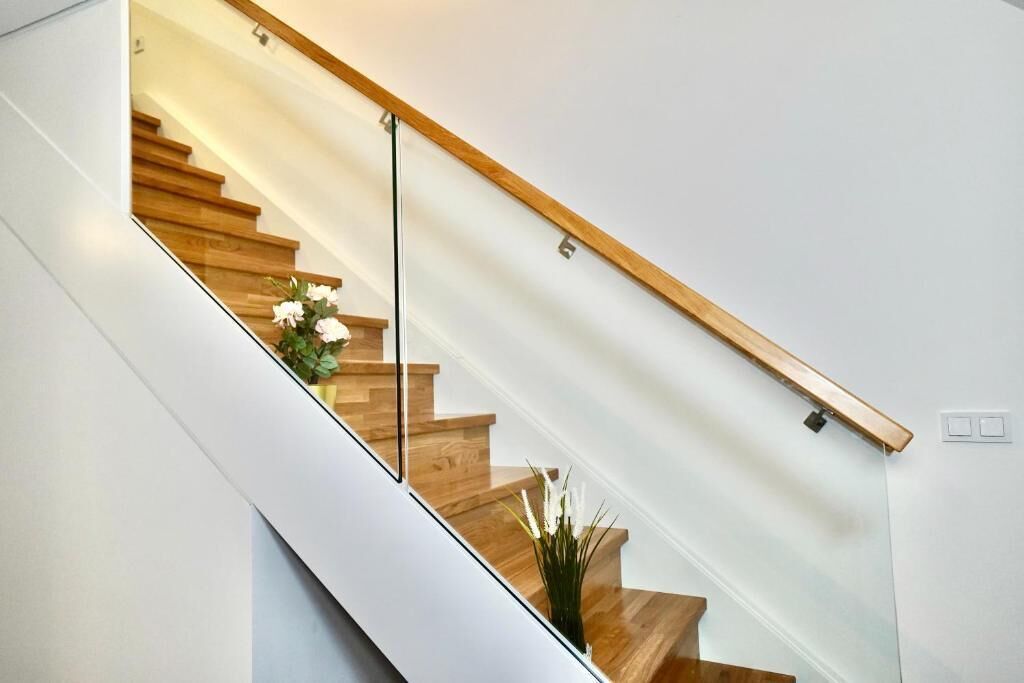 A modern staircase with wooden steps and glass railings.