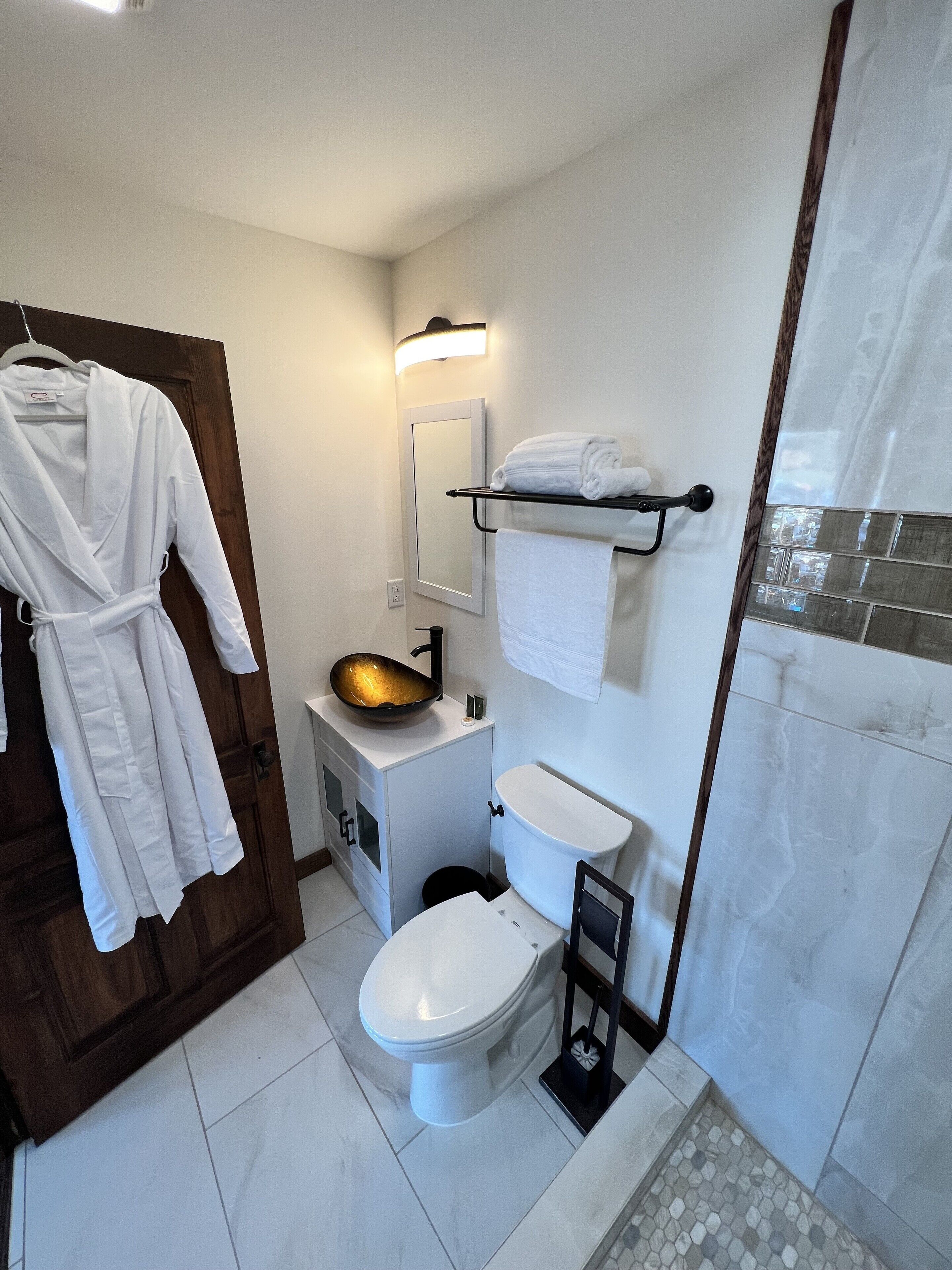 A modern bathroom with a toilet, sink, and a glass shower enclosure.