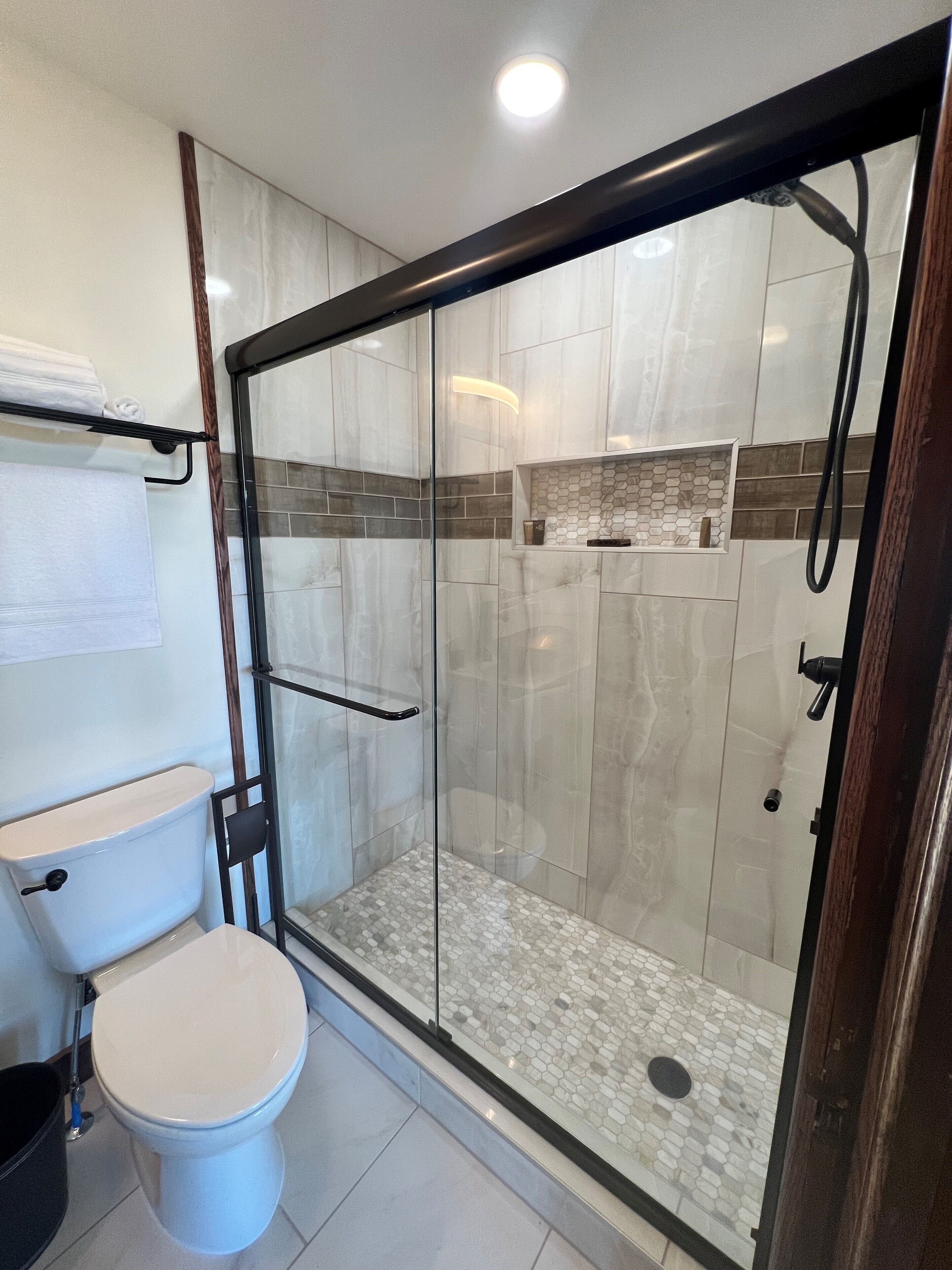 Un baño moderno con ducha de vidrio, inodoro y barra para toallas.