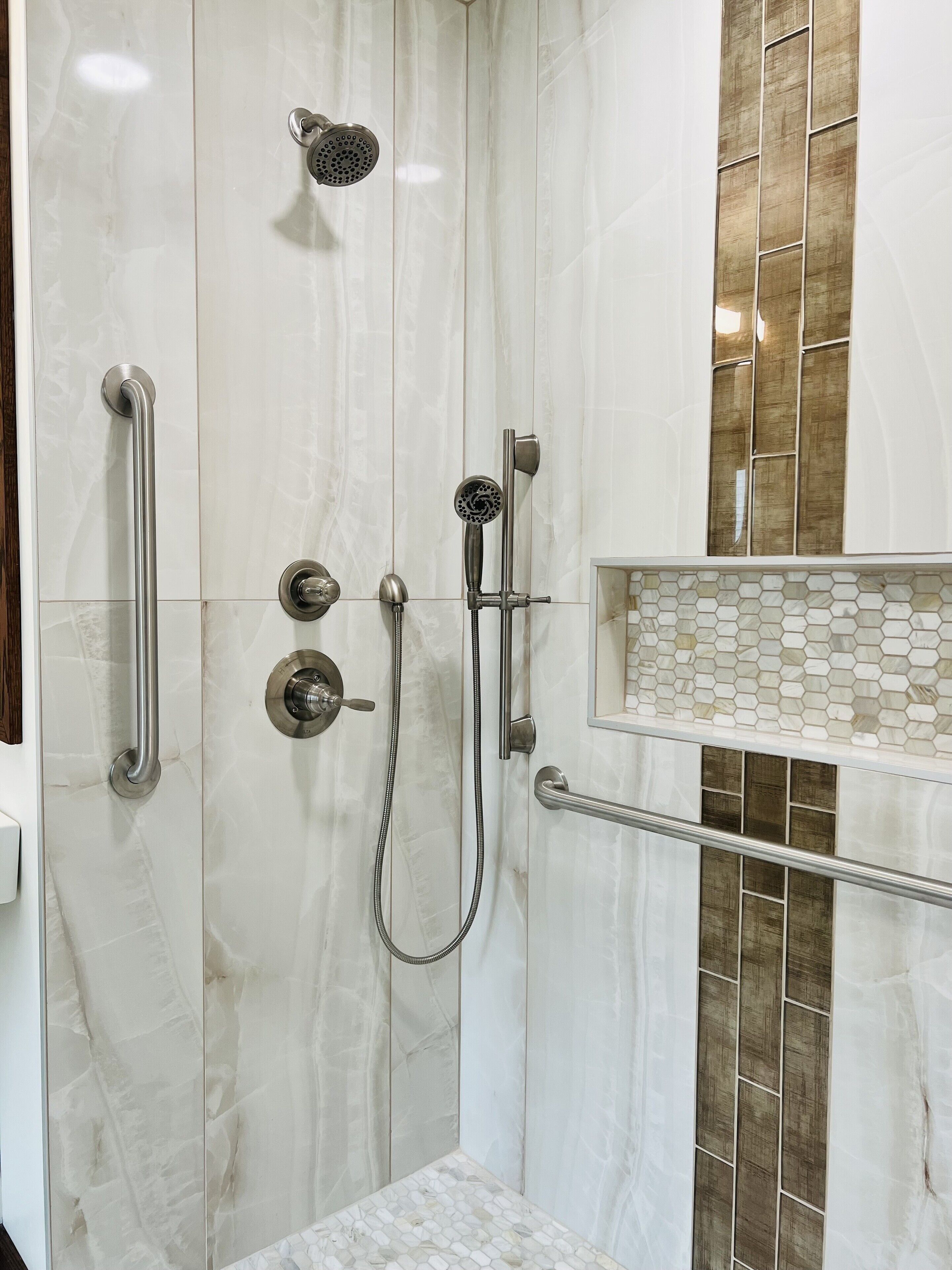 A modern shower with a handheld showerhead, a wall-mounted faucet, and a handheld showerhead.