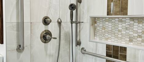 A modern shower with a handheld showerhead, a wall-mounted faucet, and a handheld showerhead.