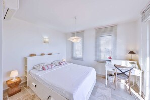Makuuhuoneessa on sänky, yöpöytä, työpöytä, tuoli ja kaksi ikkunaa, joissa on sälekaihtimet.