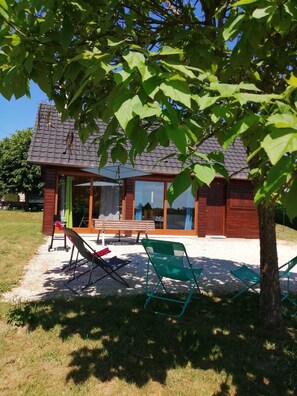 A wooden cabin with a tiled roof, a glass door, and a bench outside.