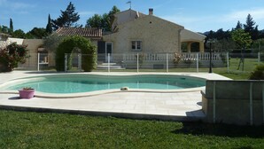 Ein Haus mit Schwimmbad, umgeben von einem Zaun und Grünflächen.