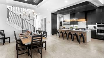 Une cuisine moderne dotée d’un îlot central, de meubles de couleur noire et d’appareils électroménagers en acier inoxydable.
