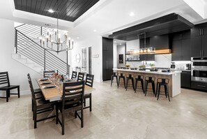 A modern kitchen with a central island, black cabinetry, and stainless steel appliances.