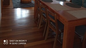 Un comedor amplio con una mesa y sillas de madera, un lámpara colgante y una ventana con cortinas.