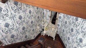 Eine Holztreppe mit strukturiertem Wandpapier und einer Kristallleuchtre.