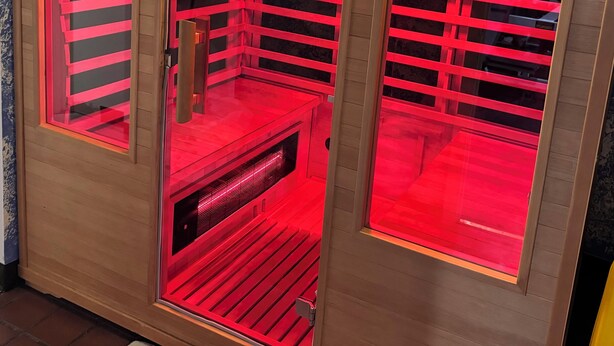 Eine Sauna mit roter Beleuchtung und einem Schild, das zum Entfernen der Schuhe auffordert.