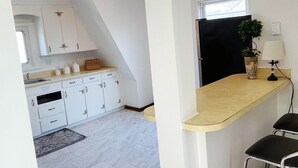 Eine Küche mit weißen Schränken, einer Holzarbeitsplatte, einer Kandelaber und einem Kühlschrank.