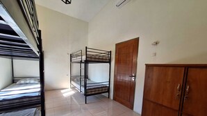 Une chambre de dortoir avec des lits superposés, une armoire en bois et une porte.