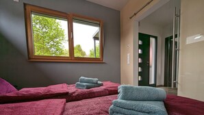 Une chambre avec deux lits, chacun recouvert d’une courtepointe à motifs et agrémenté d’une pile de serviettes. Une fenêtre offre une vue sur les arbres à l’extérieur.