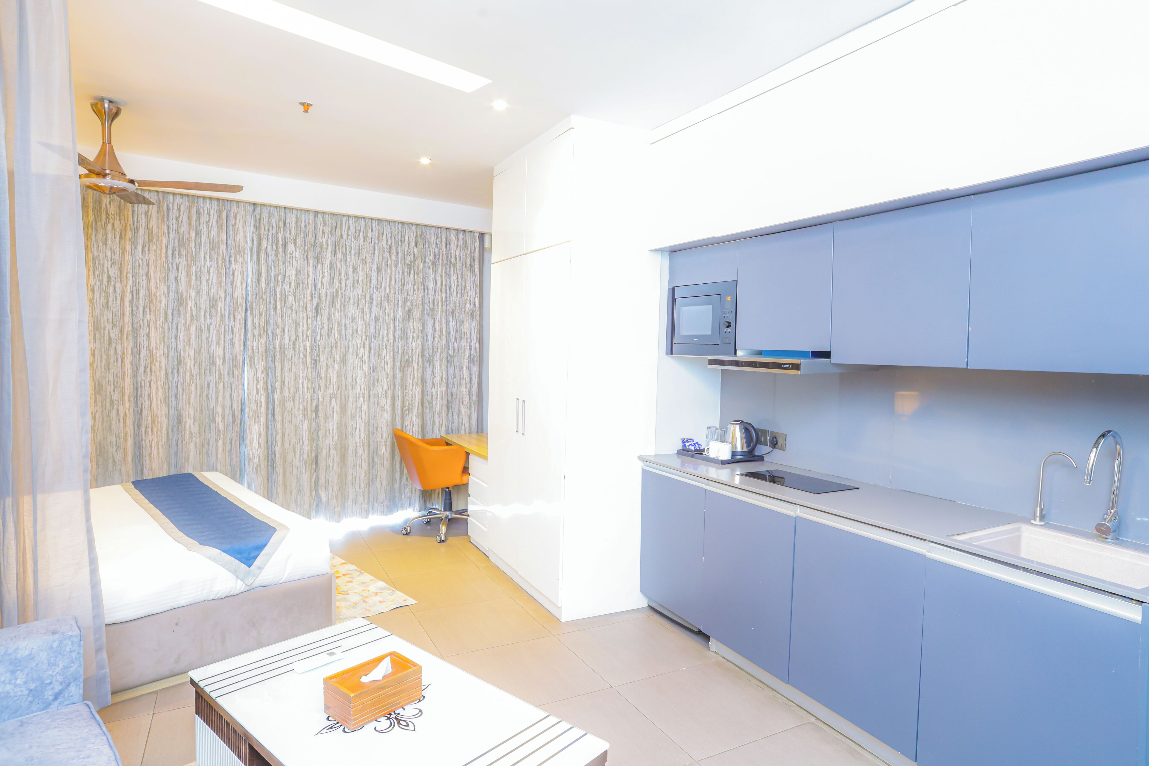 A modern kitchen with a microwave, sink, and orange chair.