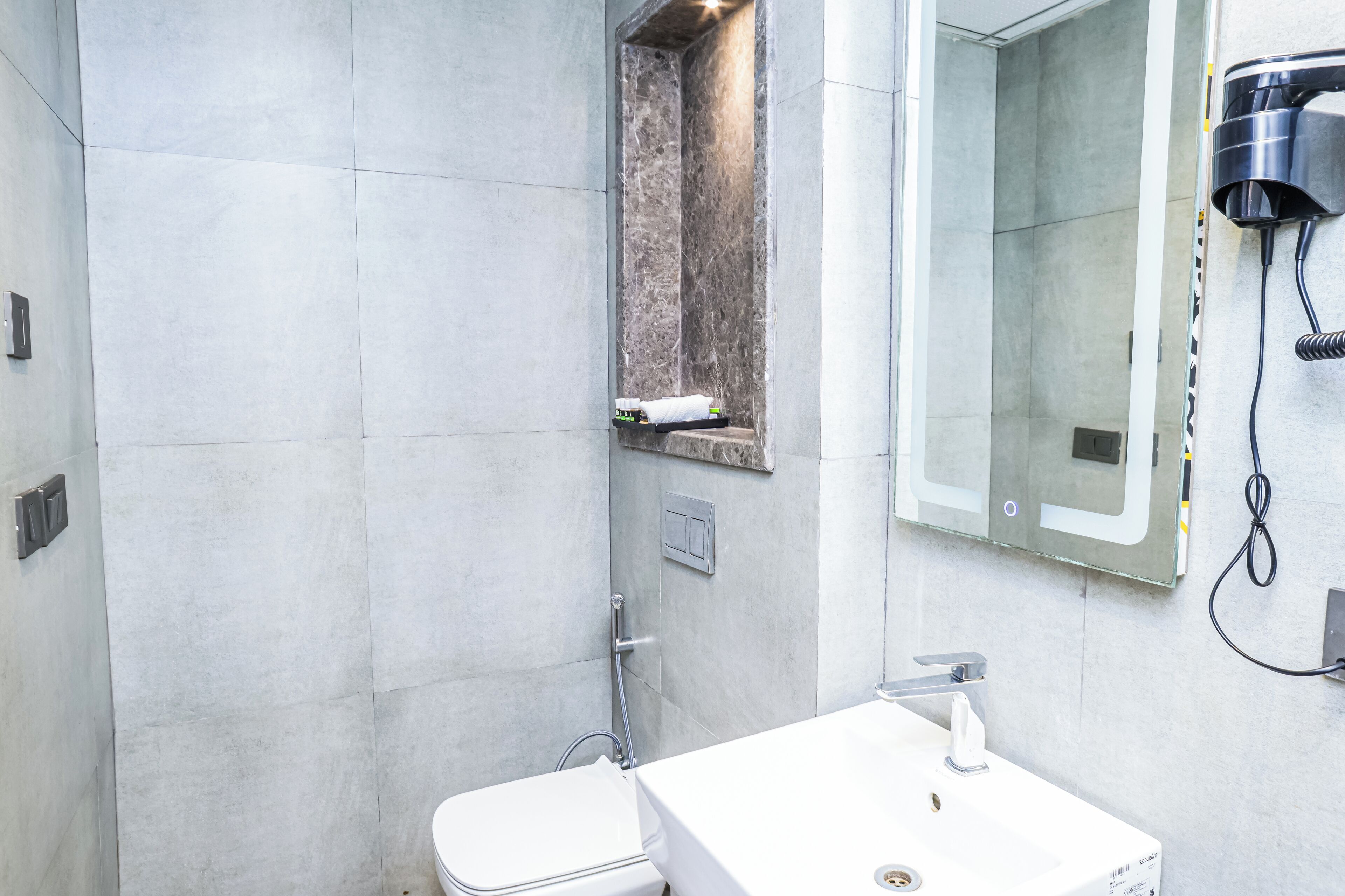 A modern bathroom with a white sink, a mirror, and a shower area.