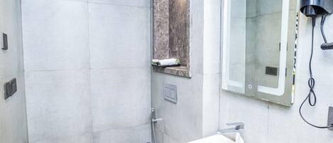 A modern bathroom with a white sink, a mirror, and a shower area.