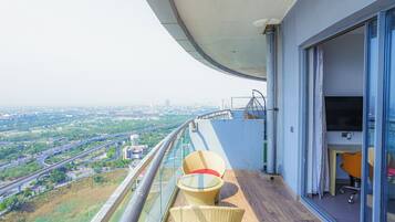 A balcony with a view of a cityscape, a glass table with chairs, and a door leading to an office area.