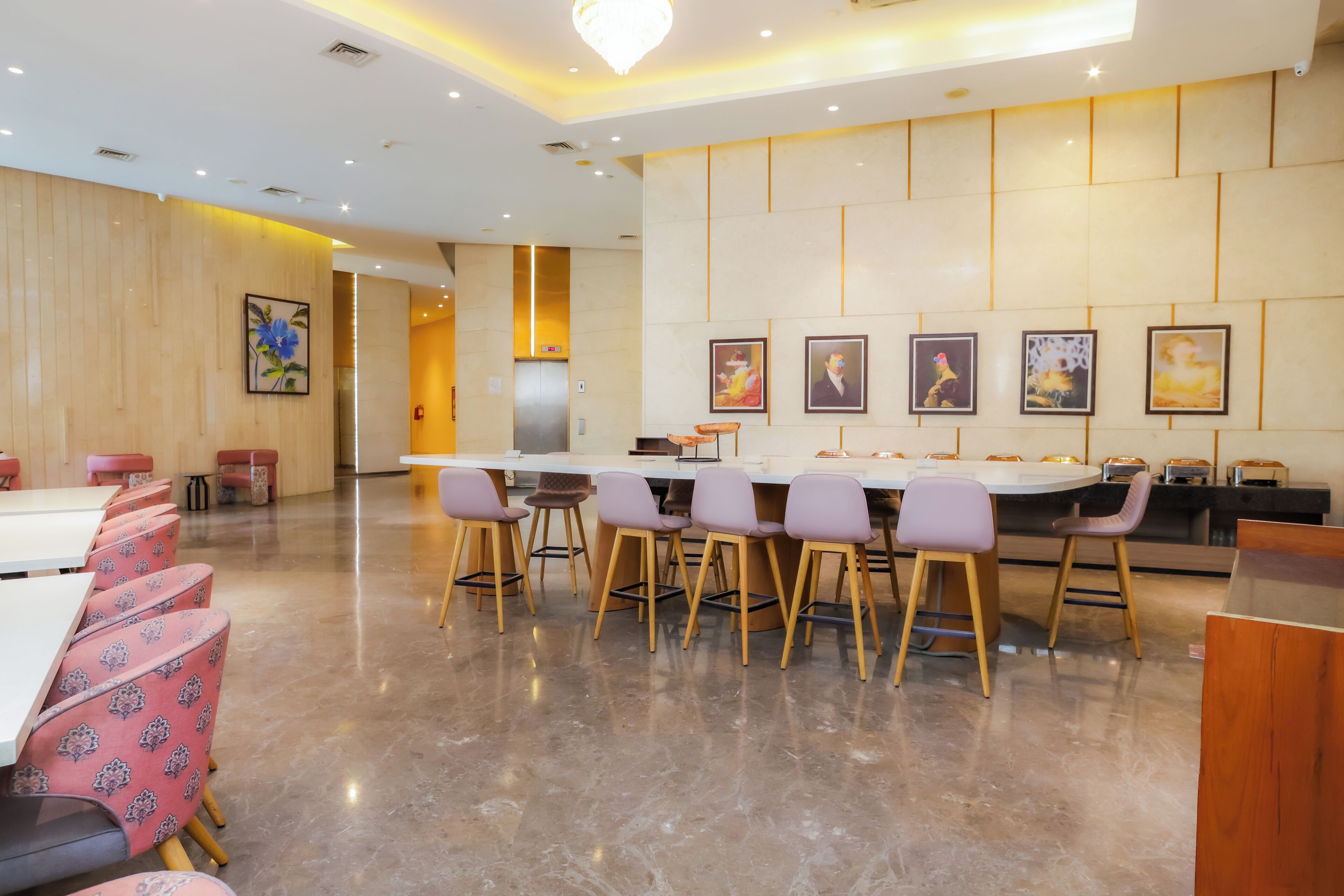 A modern dining area with a long table and multiple chairs, a reception desk, and framed artwork on the walls.
