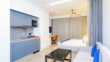 Una habitación de hotel moderna con kitchenette, un sofá, una mesa de centro y un ventilador de techo.