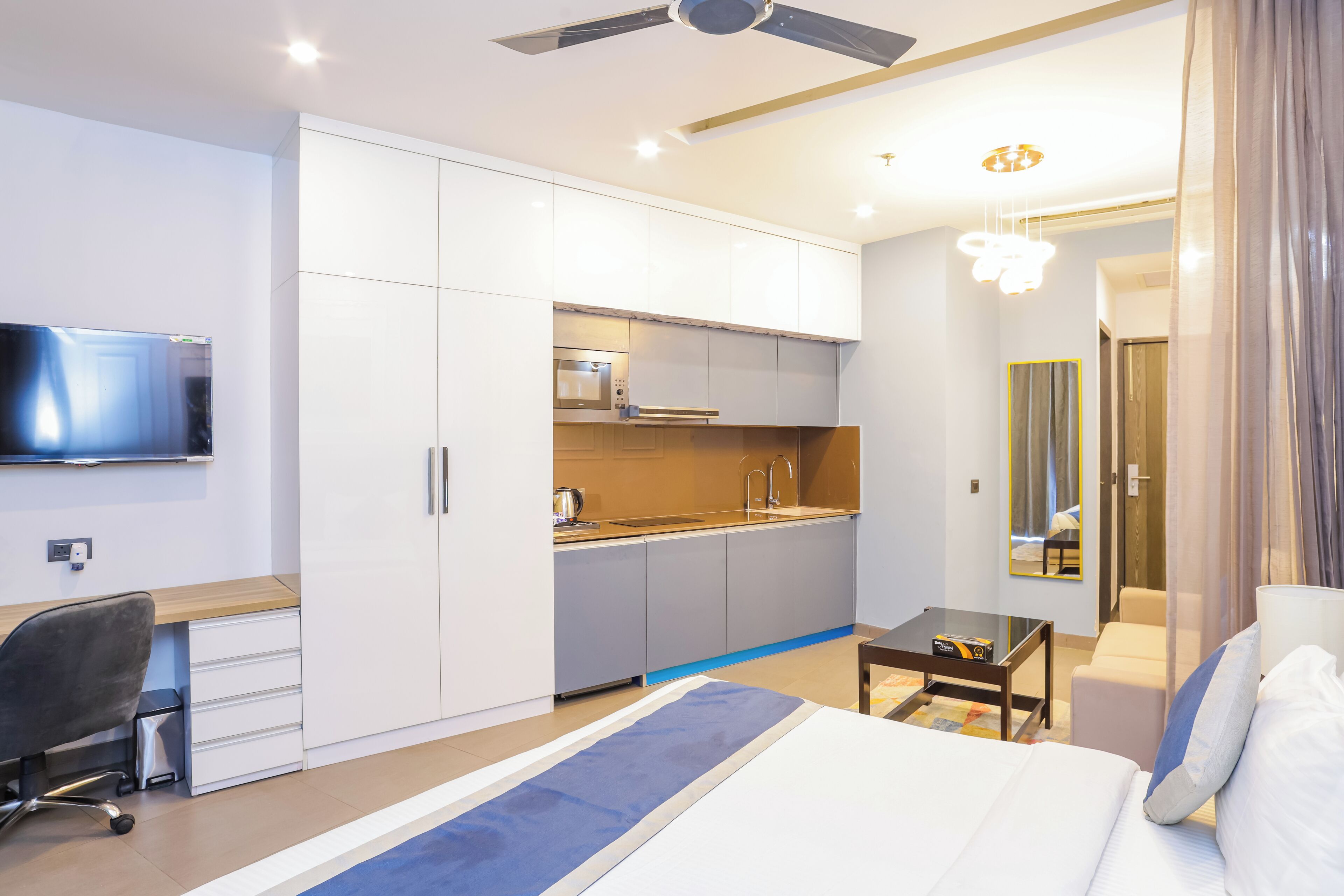 Una habitación de hotel moderna con cama, escritorio, kitchenette y televisión.