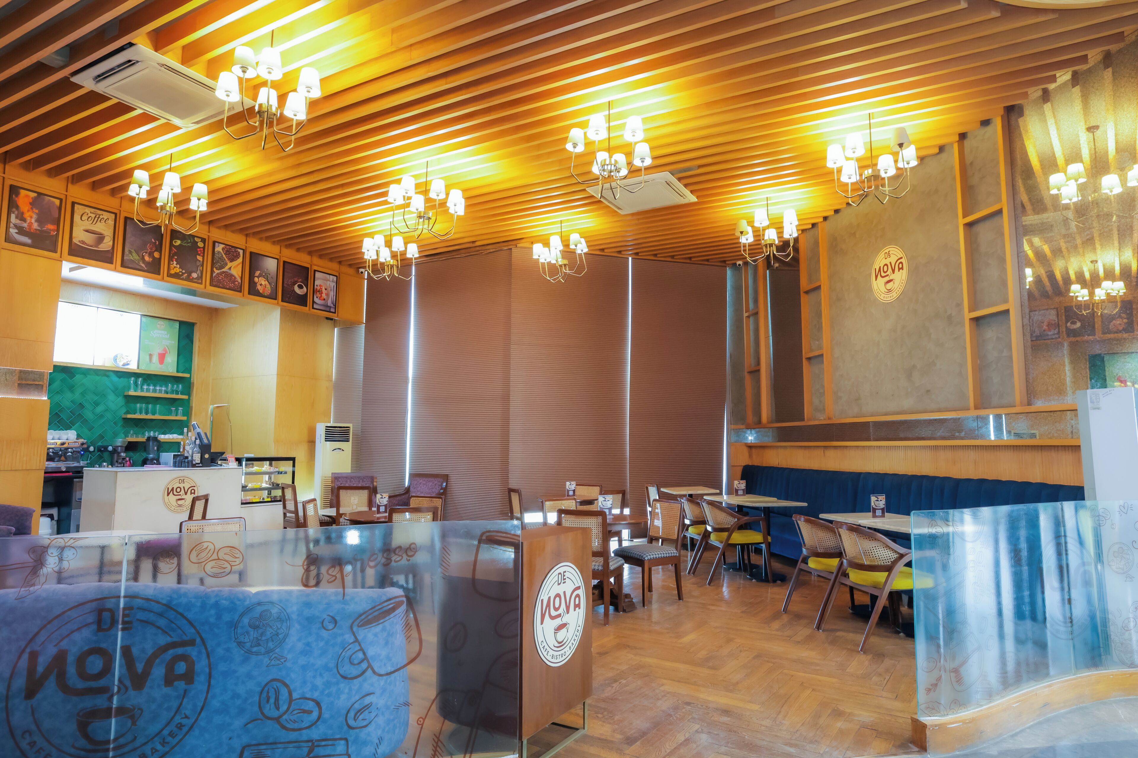 Un interior de restaurante con paneles de techo de madera, varias mesas y sillas, y una zona de mostrador.