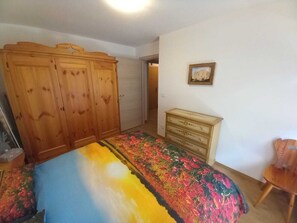 Ein Schlafzimmer mit einem Bett, einem Holzschrank, einer Kommode und einem Stuhl.