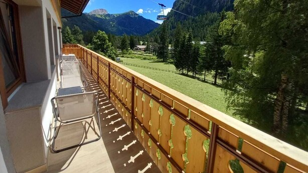 A balcony with a view of a mountain landscape, a chair, and a railing. - Cësa Giulio - near the Sellaronda ski area / Dolomites (Campitello di Fassa)
