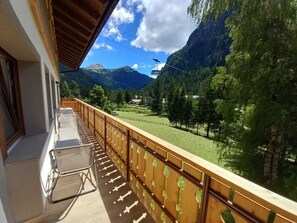 En balkon med udsigt over et bjerglandskab, en stol og et gelænder.