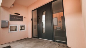 A modern entrance with a sliding glass door, a wall-mounted sign, and two small windows. - Cozy Seaside Studio Apartment C - Faraway (Lagoa)